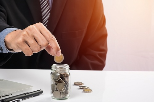 Hand putting mix coins and seed in clear bottle and copyspace, B